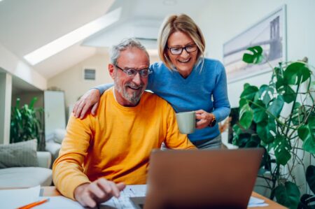 Happy senior couple creating a will on a laptop at home