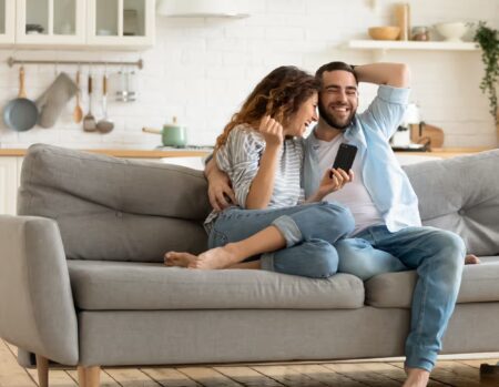 Husband and wife holding phone receiving good news of IVF grant